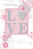 This anniversary card carries a gentle celebration of lasting love, its style perfectly suited to the tranquil charm of Downe. At the centre, the word LOVE stands out in a soft, raised glitter finish, the letters shaped with smooth curves that give them a graceful, almost handwritten feel. The O is replaced by a shimmering heart, textured with slightly denser silver glitter so it becomes the luminous focal point, as if symbolising the shared heart of a long-standing relationship. Around this central word, delicate blossoms in blush pinks and muted mauves unfurl in a loose, almost watercolour style, their edges feathery and light. Thin, swirling lines loop into vines and tendrils, creating a sense of movement much like the gentle breeze that travels across Downe's open fields and gardens. Small decorative flourishes - scattered petals, elegant curls, and a few subtle butterfly shapes - are interwoven among the blooms, suggesting whimsy and quiet joy rather than loud celebration. The background is a soft pastel pink, gently textured so it looks like high-quality card, giving the whole piece a tactile, crafted feel that pairs naturally with a bouquet of fresh flowers. In an understated, graceful script, the words On Our Anniversary and I love you today and always are written, the letters slim and flowing, echoing the affection of a personal note exchanged over many years. The overall impression is one of intimacy and warmth - a keepsake card that, like a thoughtfully arranged bouquet from Downe Flowers, marks a shared journey with tenderness, subtle beauty, and heartfelt sincerity.